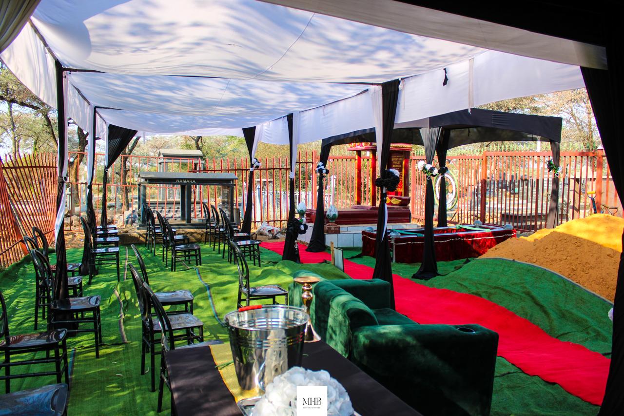 Black and white draped graveside tent with chairs, carpeting and lounge furniture