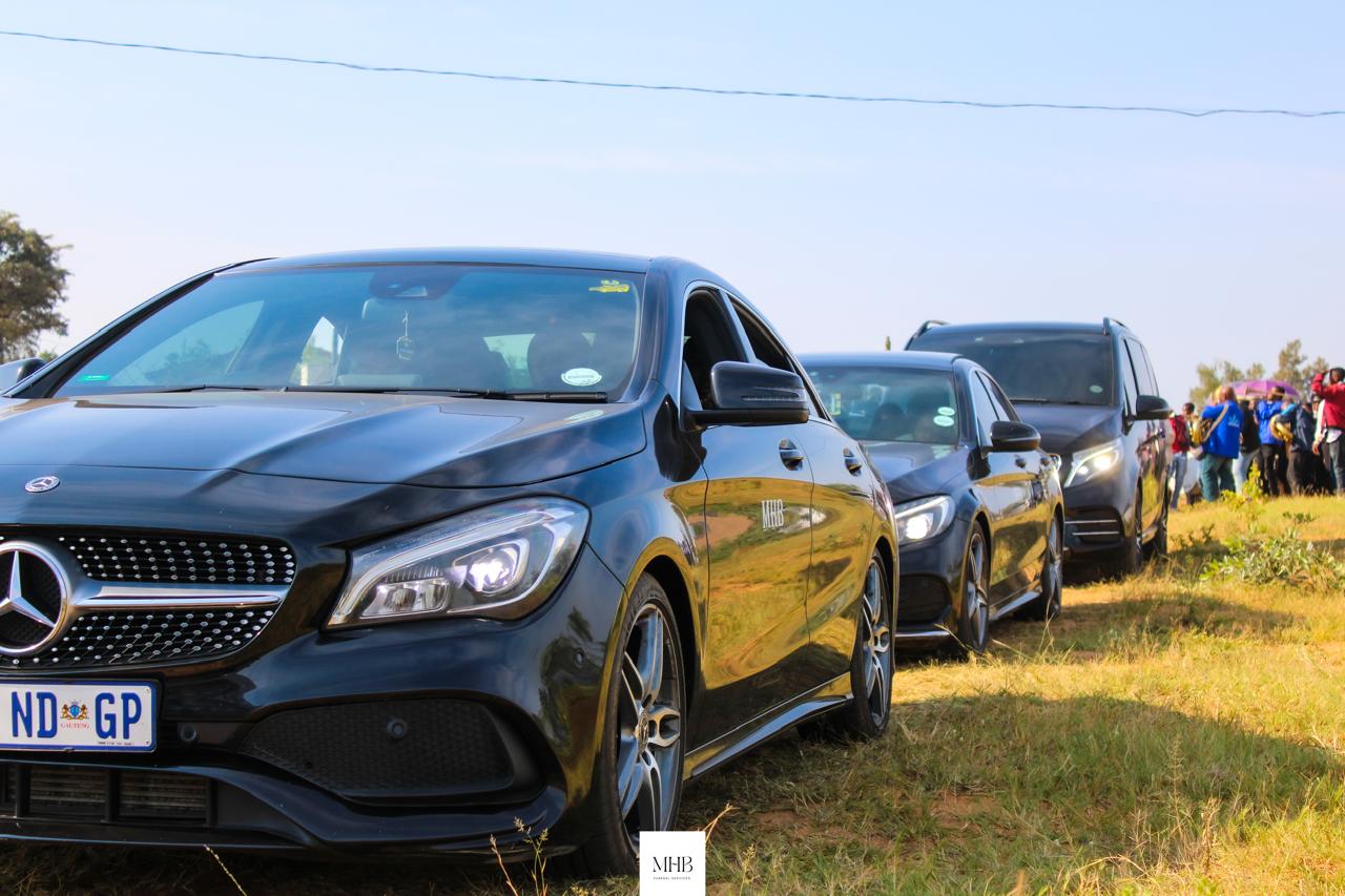 MHB Mercedes-Benz vehicles parked at a graveside in an open field