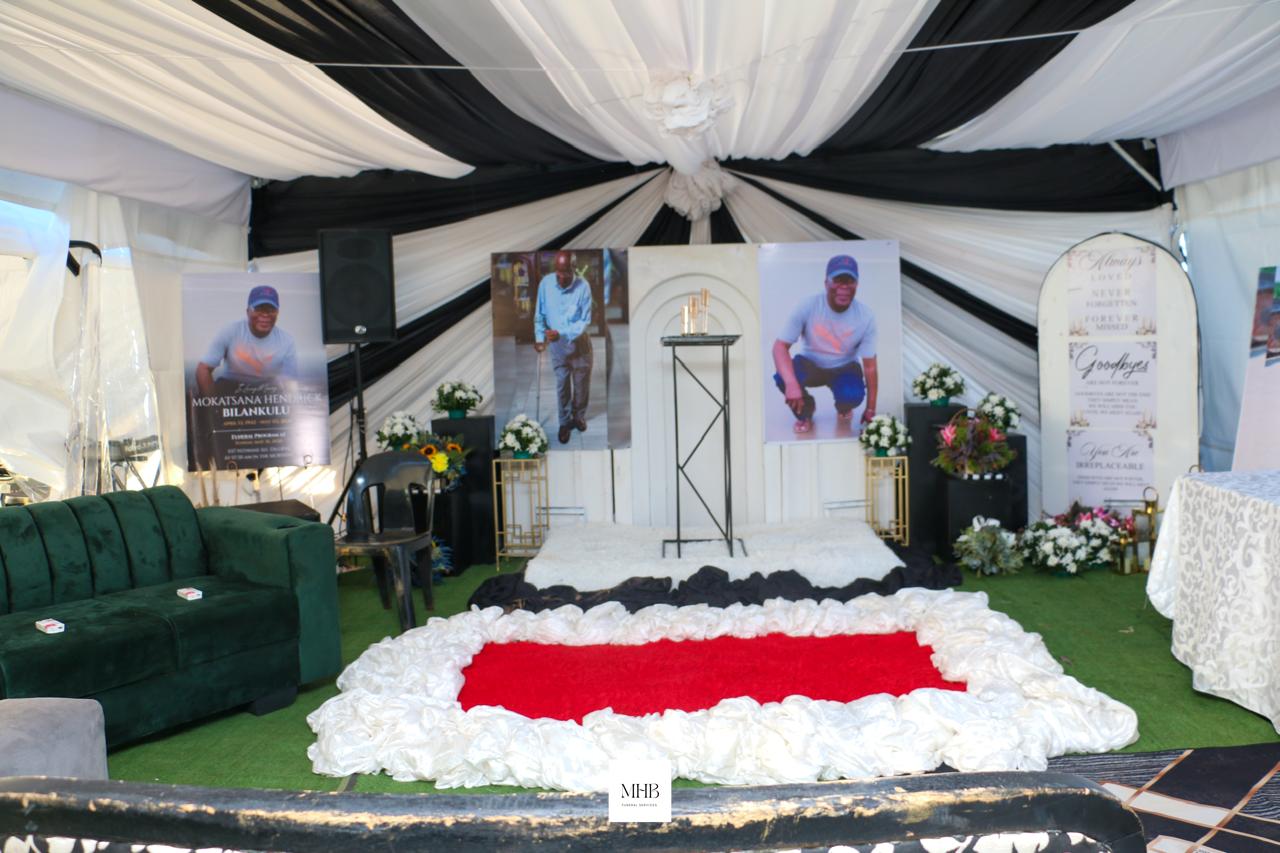 Draped memorial tent with photographs, flowers and red carpet prepared by MHB